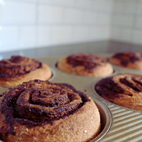 Gluten-free cinnamon rolls in a muffin tin with a blurred background