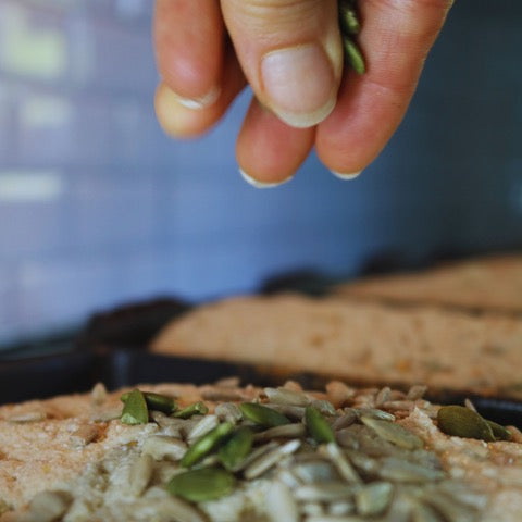 Ham dropping seeds onto a freshly baked loaf of gluten-free sourdough bread