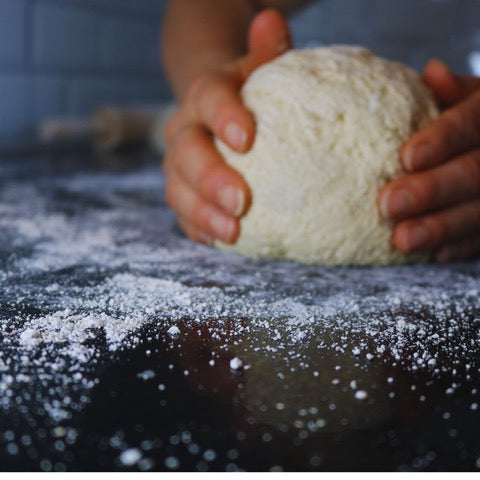 Person holding a ball of dough on a floured surface