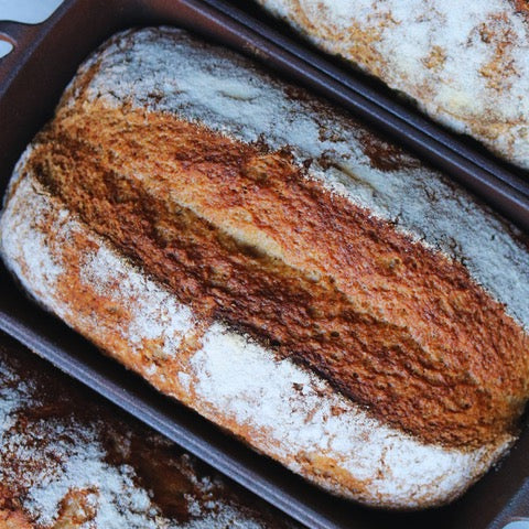 Loaf of gluten-free bread with a patterned crust in a baking tray